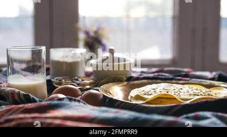 Un mucchio di frittelle calde fresche su un tavolo dorato a casa per la colazione, ingredienti per cucinare frittelle, primo piano uova biologiche. Messa a fuoco selettiva, per un'attenzione particolare Foto Stock