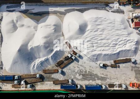 Lisbona, Portogallo - 28 marzo 2021: Vista aerea di una cava con autocarri pesanti e navi portacontainer lungo il fiume Tago nella zona industriale di li Foto Stock