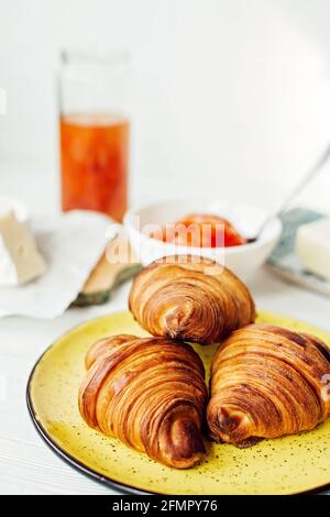 Prima colazione con croissant fresco e una tazza di latte di caffè aromatico, marmellata di mandarino, burro e formaggio brie. Colazione sana. Foto Stock