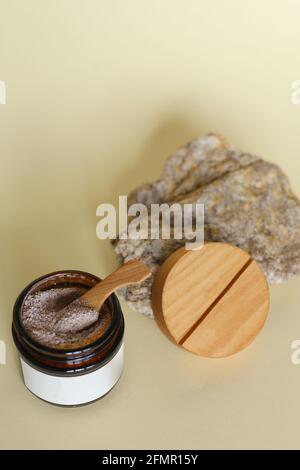 Scrub corpo di caffè macinato, zucchero e olio di cocco in vaso di vetro sul tavolo, cosmetici fatti in casa per la peeling e la cura termale Foto Stock