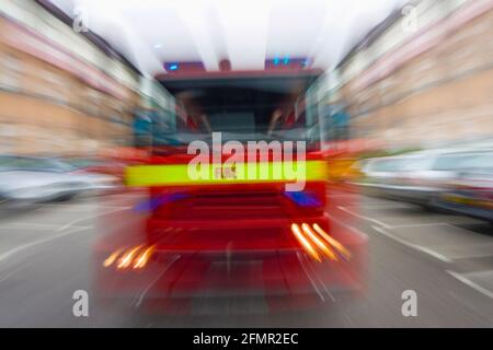 Motion fuoco offuscato motore tenero fuoco brigata veicolo in movimento a. velocità su una strada attraverso il traffico di automobili e gli edifici Foto Stock