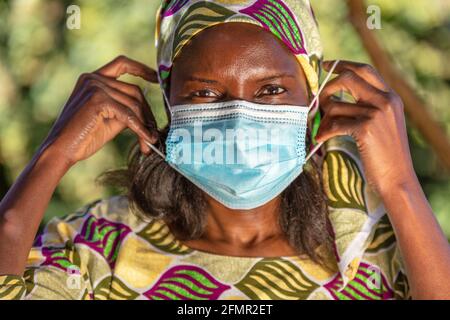 Donna africana di mezza età, donna in Africa, indossando abiti tradizionali e indossando la maschera in Coronavirus COVID-19 pandemia Foto Stock