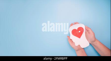Mani che tengono testa di carta e cuore. Alzheimer, colpo di cervello, giornata del cuore del mondo, giornata mondiale della salute, giornata mondiale della salute mentale e concetto di benessere Foto Stock