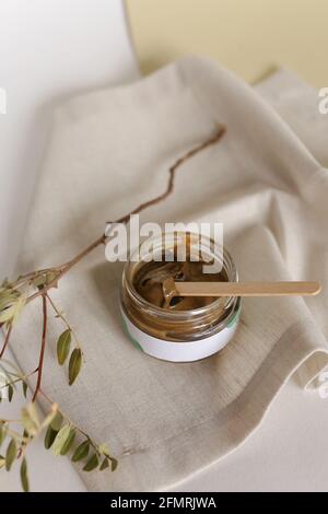 Scrub corpo di caffè macinato, zucchero e olio di cocco in vaso di vetro sul tavolo, cosmetici fatti in casa per la peeling e la cura termale Foto Stock