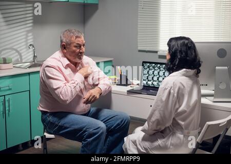 Una dottoressa che dà una prescrizione medica ad un uomo anziano. Foto Stock