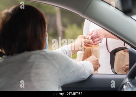 Donna in un'automobile che afferra una borsa di carta da un altro donna Foto Stock