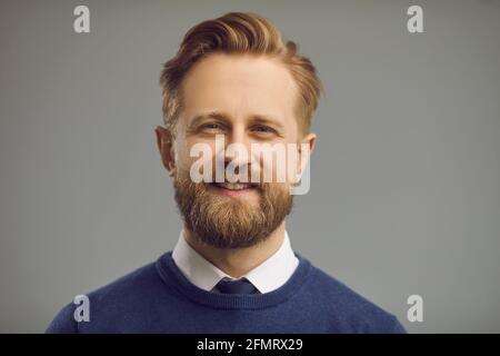 Uomo millenario sorridente che guarda il ritratto della fotocamera su grigio spazio di copia Foto Stock