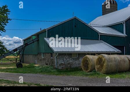 Hamilton, Ontario, Canada, agosto 2016 - granaio e silo su terreni agricoli con balle di fieno accatastate davanti Foto Stock