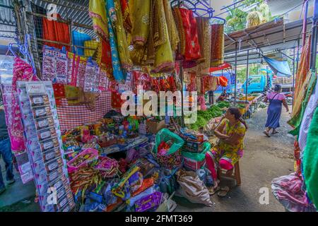 Isola di Mauritius, Oceano Indiano, Dicembre 2015 - venditrice locale femminile, con vari prodotti esposti per la vendita in un mercato aperto Foto Stock