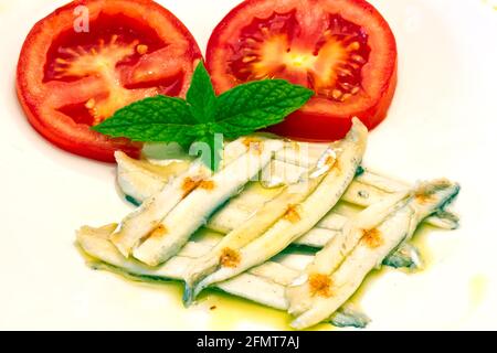 razione di acciughe in aceto, guarnite con pomodoro e menta Foto Stock