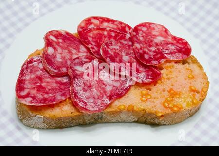 Pomodoro in stile catalano strofinato su una fetta di pane con olio e punto di sale, circa il flagello dello stile rurale. Foto Stock