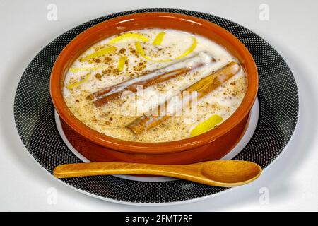 Piatto di budino di riso con cannella grattugiata, con graffi al limone. Su piatto e cucchiaio di legno Foto Stock