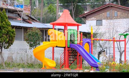 Colorato parco giochi e antico casale in stile vintage e il tetto fatto di mattoni rossi sfondo. Foto Stock