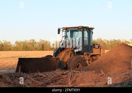 Un caricatore frontale Caterpillar in un campo con una pila di sporcizia pronta per lavorare a nord di Lione, Kansas USA, in una giornata colorata. Foto Stock