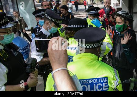 Londra, Regno Unito. 11 Maggio 2021. Gli ufficiali della polizia metropolitana cercano un attivista dall'altra parte della strada da una protesta di Palestine Action al di fuori del quartier generale britannico di Elbit Systems, un'azienda israeliana che sviluppa tecnologie utilizzate per applicazioni militari tra cui droni, guida di precisione, sorveglianza e sistemi di rilevamento di intrusi. Gli attivisti protestavano contro la presenza dell'azienda nel Regno Unito e in solidarietà con il popolo palestinese in un momento di notevole aumento della tensione in Israele e nei territori occupati a seguito di tentativi di sfratto forzato delle famiglie palestinesi i Foto Stock