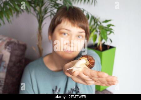 La lumaca di Ahatina striscia sulla mano di una donna Foto Stock