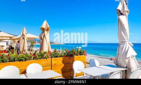 Una caffetteria fronte spiaggia con patio esterno lungo la spiaggia del Casino o la Plage du Casino lungo la Riviera Francese nella città di Menton, in Francia, in estate. Foto Stock