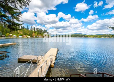 Un piccolo molo da una casa nella comunità rurale di Newman Lake, Washington, USA con altre case sul lungomare e scivoli in vista. Foto Stock