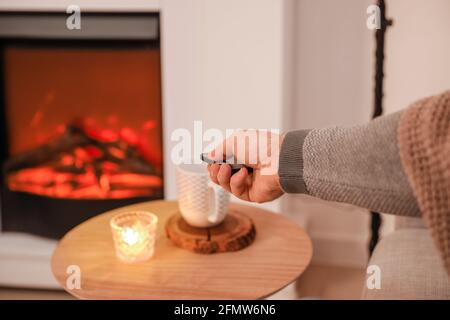 Uomo che regola il camino elettrico a casa Foto Stock