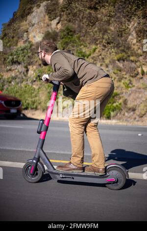 Uomo che cavalca veloce uno scooter elettrico con vigore, Wellington Nuova Zelanda Foto Stock