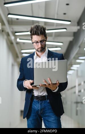Giovane uomo d'affari in ufficio lavoro on-line su laptop risolvere il problema aziendale. Uomo d'affari pensivo usare il computer che pensa a riflettere sul progetto. Foto Stock