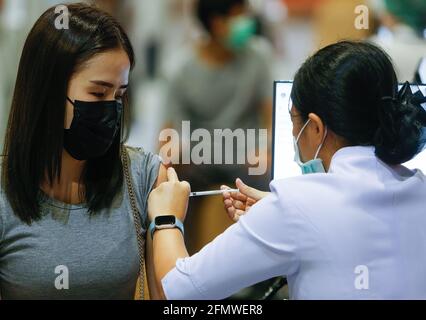 Un operatore sanitario inocula una donna con una dose di vaccino CoronaVac a Bangkok. Secondo un alto funzionario del Ministero della Sanità pubblica, le autorità sanitarie puntano ora a ottenere circa il 70% dei residenti della capitale, ovvero circa 5 milioni di persone vaccinate contro Covid-19 in due mesi. La mossa seguita dal primo ministro Prayut Chan-o-cha martedì ha espresso preoccupazione durante la riunione del gabinetto per il fatto che il numero di persone che si sono registrate per le vaccinazioni con il governo era al di sotto del target. (Foto di Chaiwat Subprasom/SOPA Images/Sipa USA) Foto Stock