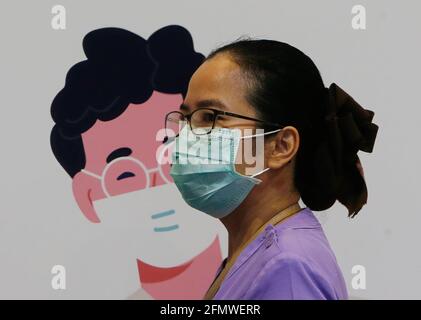Un'infermiera che indossa una maschera facciale passa accanto a un poster presso il centro di vaccinazione di Bangkok. Secondo un alto funzionario del Ministero della Sanità pubblica, le autorità sanitarie puntano ora a ottenere circa il 70% dei residenti della capitale, ovvero circa 5 milioni di persone vaccinate contro Covid-19 in due mesi. La mossa seguita dal primo ministro Prayut Chan-o-cha martedì ha espresso preoccupazione durante la riunione del gabinetto per il fatto che il numero di persone che si sono registrate per le vaccinazioni con il governo era al di sotto del target. (Foto di Chaiwat Subprasom/SOPA Images/Sipa USA) Foto Stock