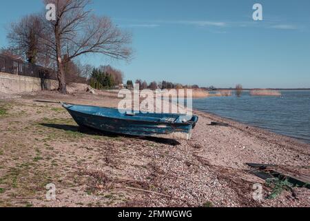 blue boat su una spiaggia rocciosa vicino al lago Foto Stock