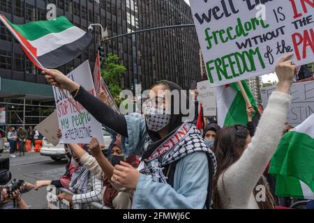 Una donna ondeggia la bandiera palestinese di fronte al consolato israeliano a Manhattan. Le ostilità tra Israele e Hamas sono salite di notte, con 35 palestinesi uccisi a Gaza e 5 in Israele negli scambi aerei più intensi per anni. L'Israele centrale è stato colpito da una massiccia ondata di razzi da Gaza, poco dopo che Hamas ha avvertito di una sbarramento nell'area di Tel Aviv se l'IDF non ha fermato gli attacchi aerei che hanno colpito edifici civili all'interno della striscia di Gaza. Secondo l'IDF, 300 razzi sono stati sparati dalla striscia di Gaza entro 18 ore. Hamas è designato come gruppo terroristico dagli Stati Uniti e dall'UE Foto Stock