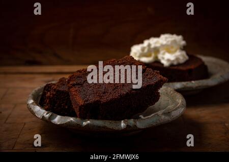 torta di cioccolato fatta in casa o browny con crema su legno tavolo, mangiare malsano Foto Stock