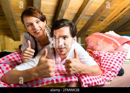 Coppia giovane a letto sul pavimento di una stalla o di una baita di montagna nelle Alpi godendo il tempo libero Foto Stock