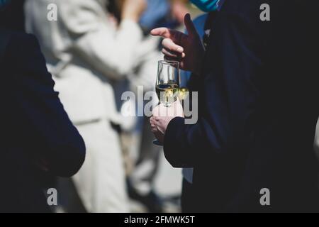 Dettagli con un uomo e una donna che interagiscono in un evento di classe, mentre si tiene un bicchiere di vino. Foto Stock