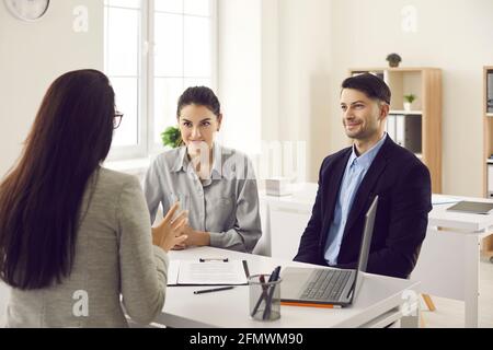 Millenaria coppia caucasica ascoltando la presentazione di una consulente finanziario femminile Foto Stock
