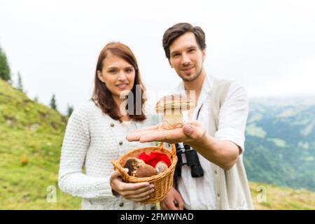 Funghi - coppia giovane cerca e ricerca di funghi porcini in montagna Foto Stock