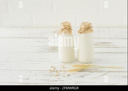 Latte di avena in bottiglie di vetro su un tavolo di legno. Latte di proteing all'organig fatto in casa Foto Stock