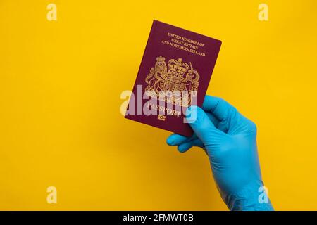 Persona che indossa guanti protettivi con passaporto di viaggio Foto Stock