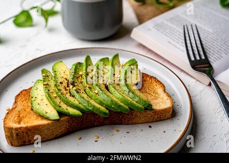 Primo piano dei deliziosi avocado affettati sul tostato pane sul piatto Foto Stock