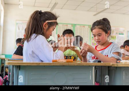 Studenti primari che lavorano su un'attività artistica e artigianale in una scuola rurale a Qufu, Shandong, Cina. Foto Stock