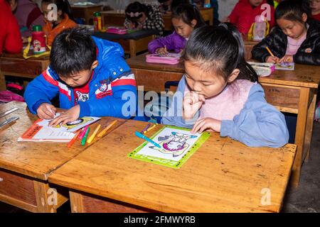 Studenti di una scuola elementare nella Cina rurale che lavorano su un progetto artistico e artigianale. Foto Stock