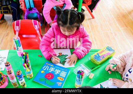 Studenti di una scuola elementare nella Cina rurale che lavorano su un progetto artistico e artigianale. Foto Stock