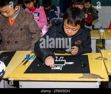 Gli studenti primari di una scuola rurale di Xiuning, Anhui, Cina che fanno opere d'arte. Foto Stock