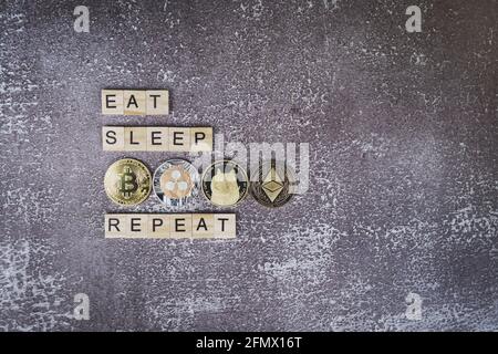 Mangia il sonno cripto ripetere, divertente segno sulle criptovalute, blocchi di legno con Bitcoin, XRP, Dogecoin e monete etereum su sfondo grigio Foto Stock