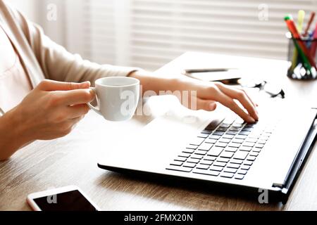 Vista dall'alto di Young Woman che naviga su Internet, codifica, shopping online, primo piano sulla tastiera del suo laptop sulla scrivania in legno testurizzato per ufficio. Sho. Sospeso Foto Stock
