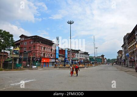 Srinagar, India. 12 maggio 2021. Le donne del Kashmiri che indossano le maschere del viso camminano attraverso una strada deserta durante un coprifuoco stretto imposto a seguito dell'impennata in casi di COVID-19 in Srinagar. Un giorno dopo che diverse aree della valle del Kashmir hanno assistito a un enorme impeto di persone prima del festival dell'Eid, è stato imposto un severo coprifuoco nella valle, mentre le autorità hanno imposto il blocco per contenere un allarmante aumento dei casi di coronavirus. Nel frattempo, l'India ha registrato 348,421 nuovi casi COVID-19 e 4,200 decessi nelle ultime 24 ore. (Foto di Saqib Majeed/SOPA Images/Sipa USA) Credit: Sipa USA/Alamy Live News Foto Stock