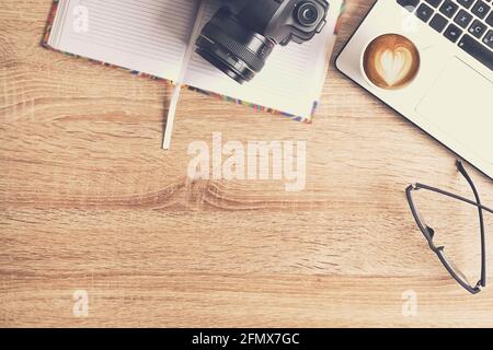 Concetto di scrivania per fotografi. Vista dall'alto del tavolo dei designer con computer portatile pc, tavoletta da disegno, fotocamera, cellulare gadget, tazza di caffè, Foto Stock