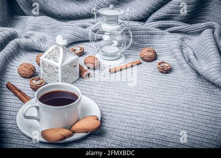 Bella plaid, una tazza con caffè e biscotti su un tavolo con candele. Foto Stock