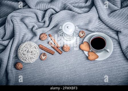 Bella plaid, una tazza con caffè e biscotti su un tavolo con candele. Foto Stock