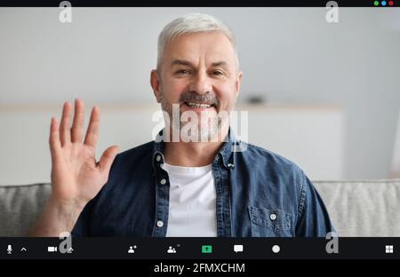 Bell'uomo anziano che ha una videoconferenza, sventolando alla telecamera Foto Stock