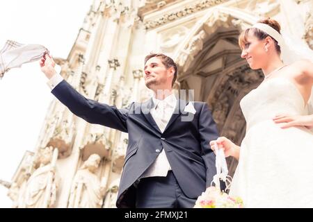 Sposa sorridente guardando sposo battenti igienico in aria esterna Foto Stock