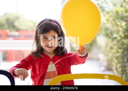 Ritratto di una bambina di quattro anni che tiene in mano un pallone. Bambina che si diverte con un pallone. Foto Stock